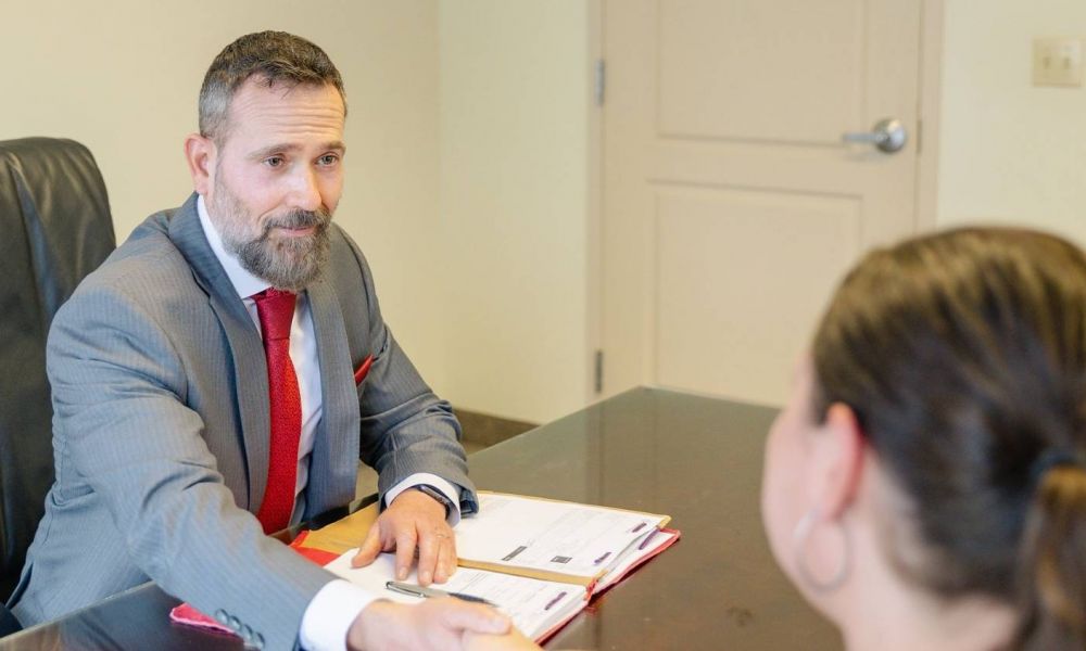Jon Montagna personal injury lawyer shakes the hand of a client as they sit in front of a desk