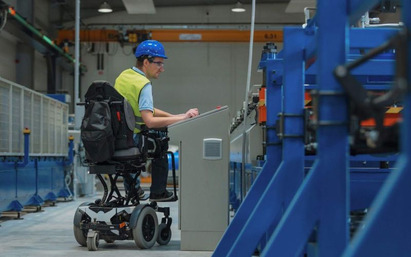 a man in a wheel chair working on a piece of equipment