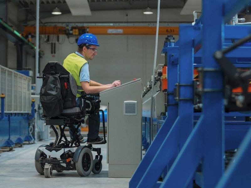 a man in a wheel chair working on a piece of equipment