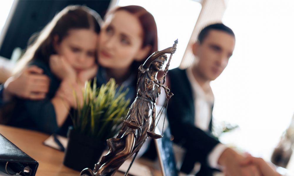 Bronze statue of Themis stands on table, behind which sits divorcing parents with little girl