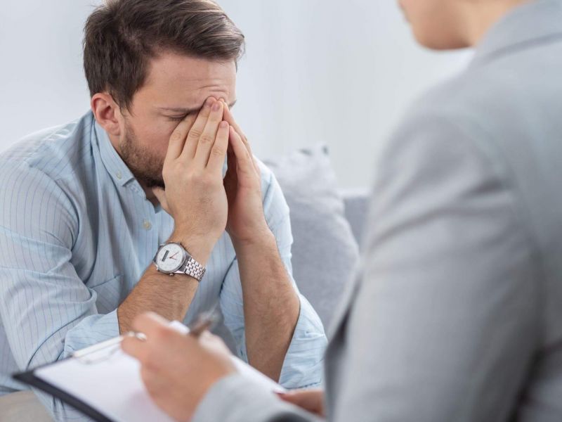 Man sitting on couch with hand on face