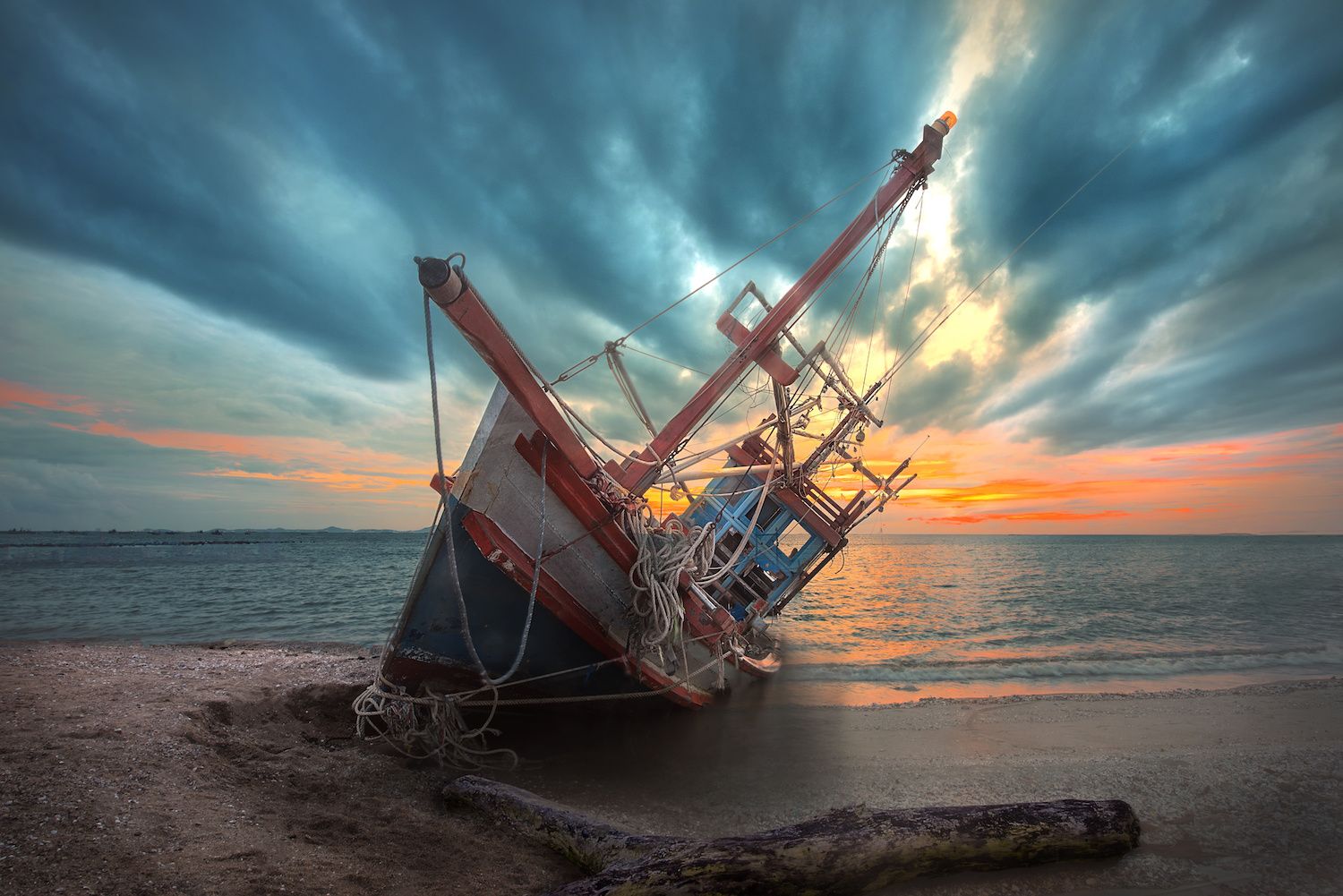 an old useless fishing boat laying dead on the sea beach at sunset scenery in background