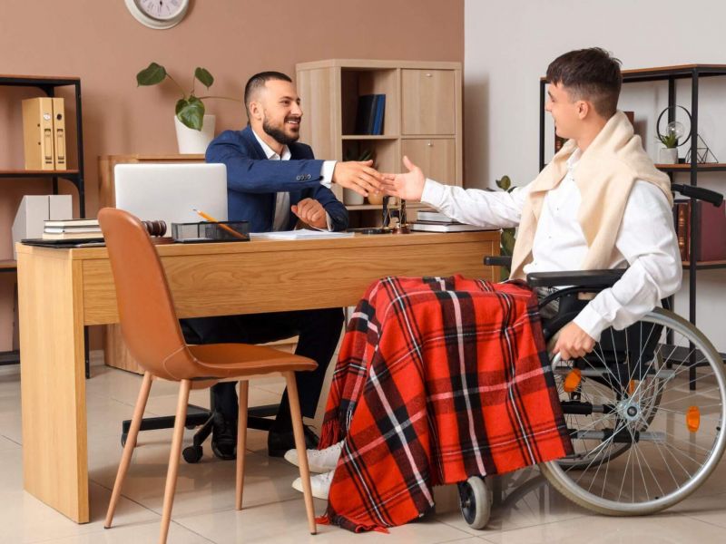 a man in a wheelchair shaking hands with another man