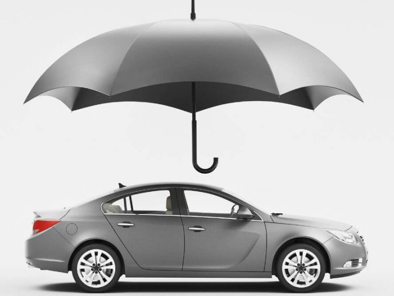 A gray car is sheltered under a large, gray umbrella, symbolizing protection. This image illustrates the concept of uninsured motorist reforms, highlighting the protection and security offered to drivers under the new policies in Virginia for 2024
