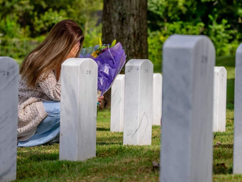 a woman kneeling down next to a bunch of headstones
