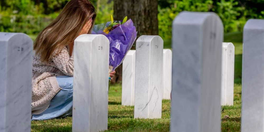 a woman kneeling down next to a bunch of headstones