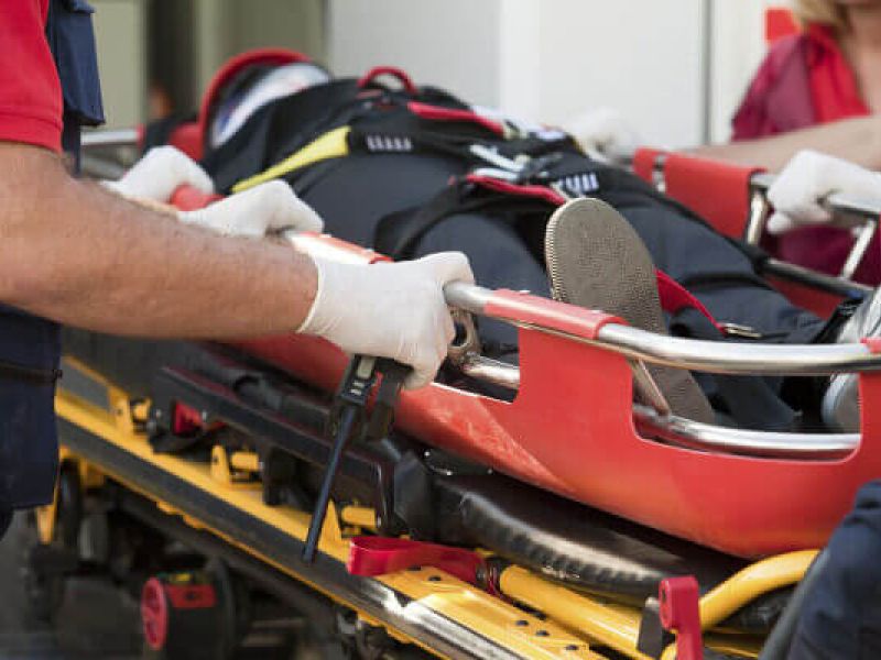 Paramedics securing a patient on a stretcher for emergency transportation.
