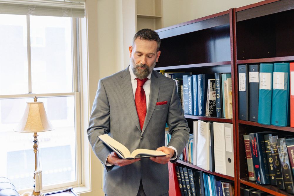 Jon Montagna reading a law book in front of a bookshelf in his personal injury law office.