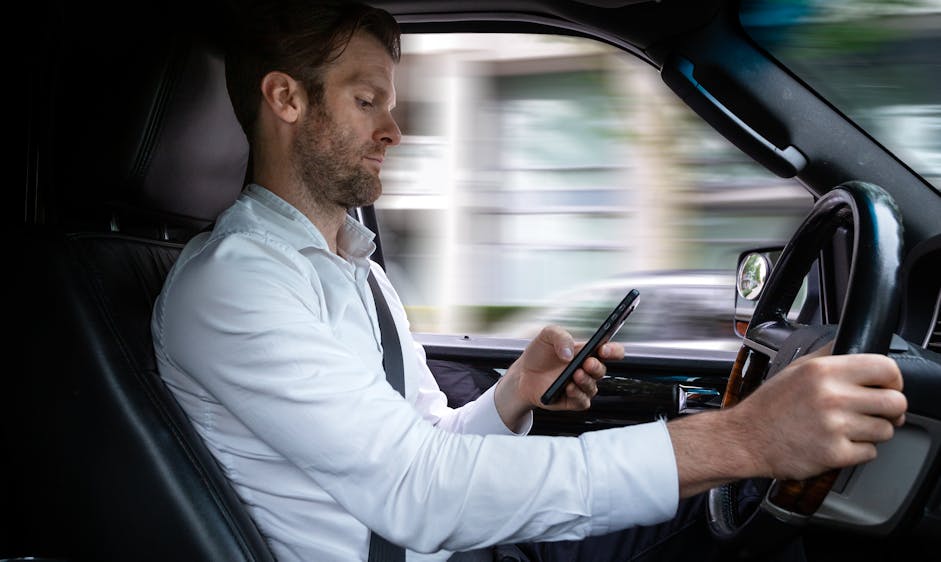 Driver looking at phone while driving, illustrating distracted driving and smartphone use risk.