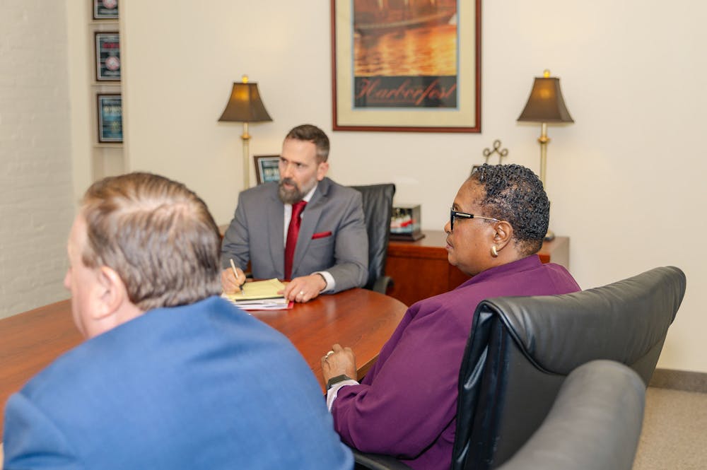 Three professionals in a business meeting around a conference table, engaged in a serious discussion.
