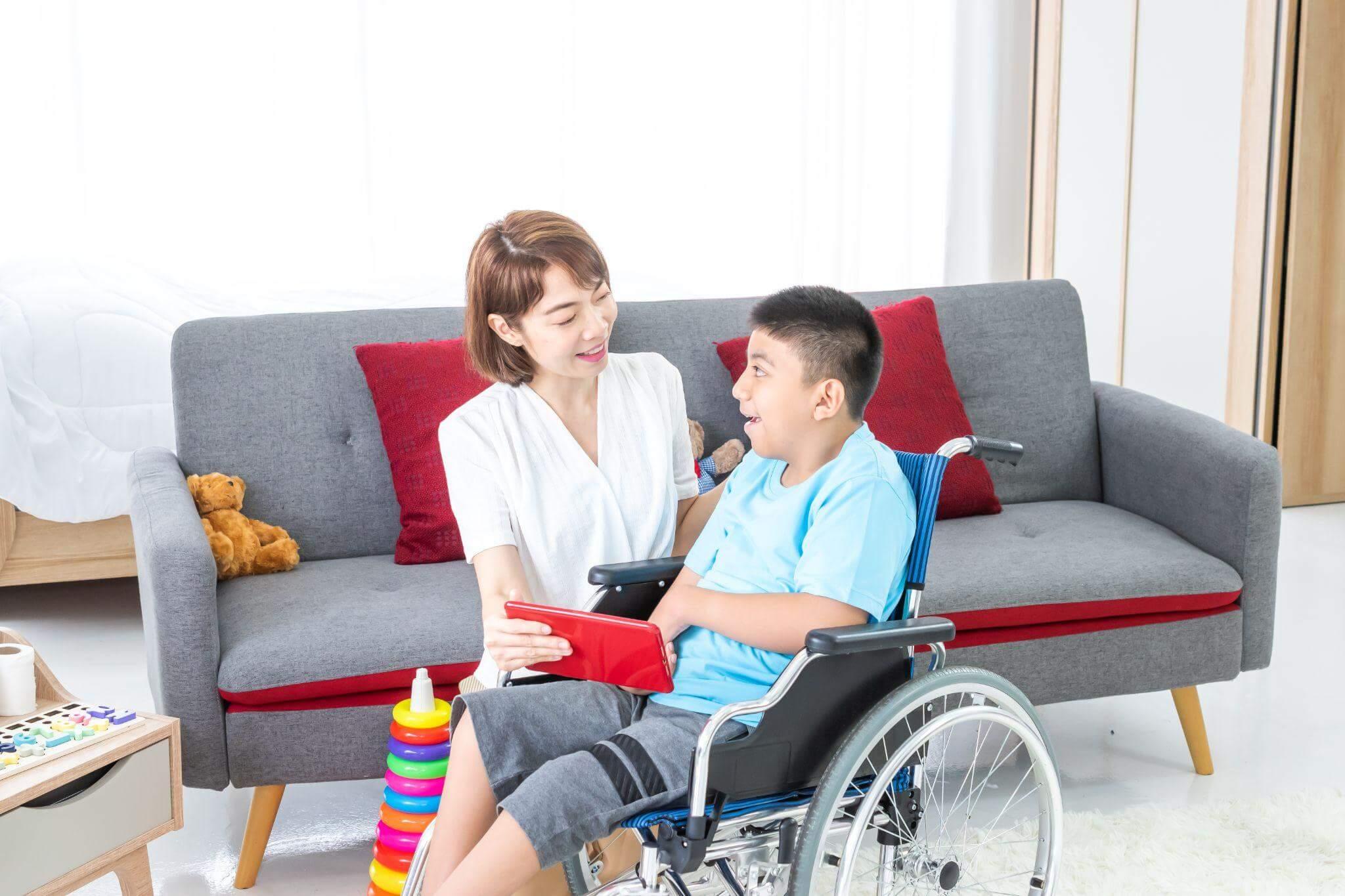a woman sitting on a couch next to a boy in a wheelchair