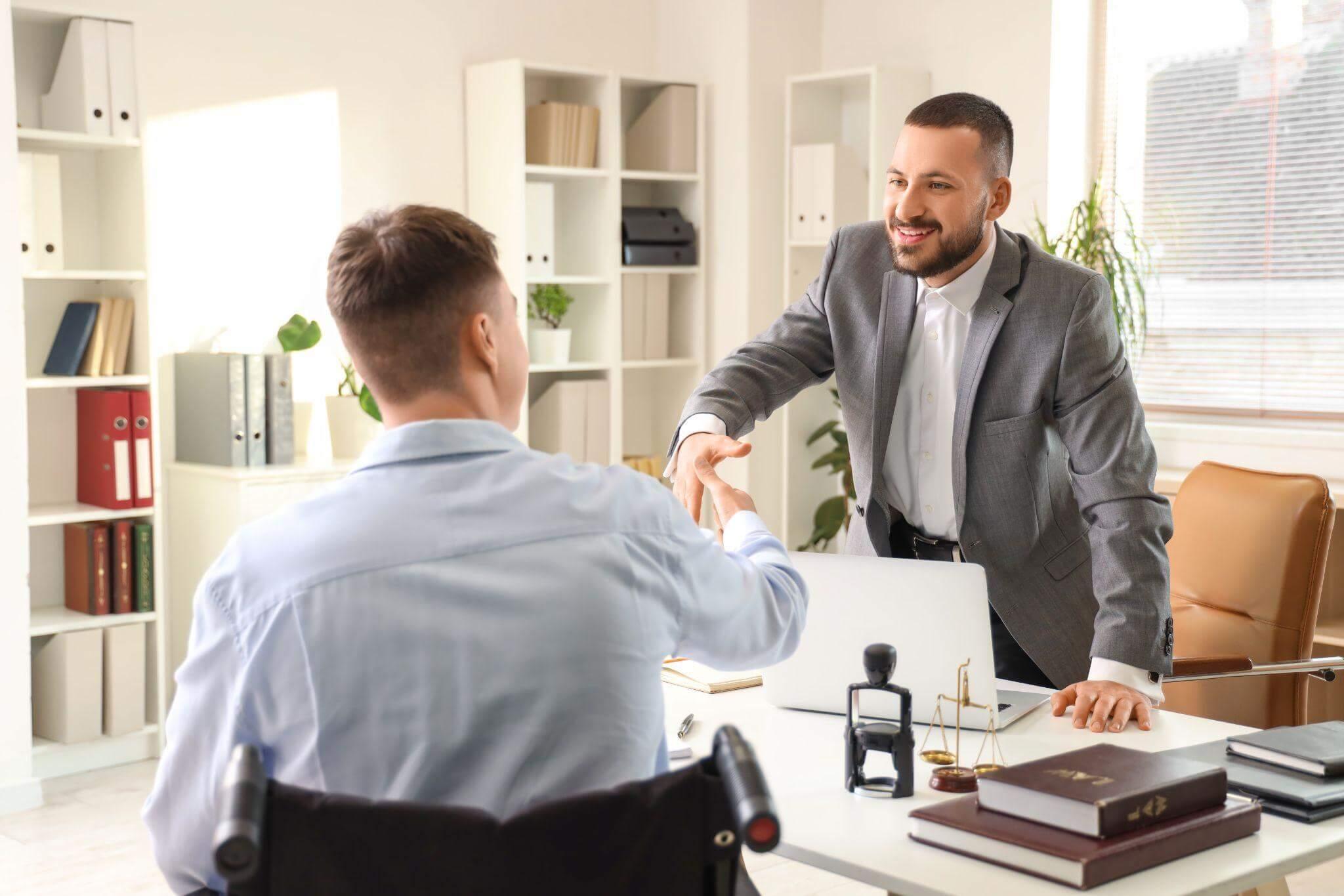 a man in a wheelchair shaking hands with a man in a suit