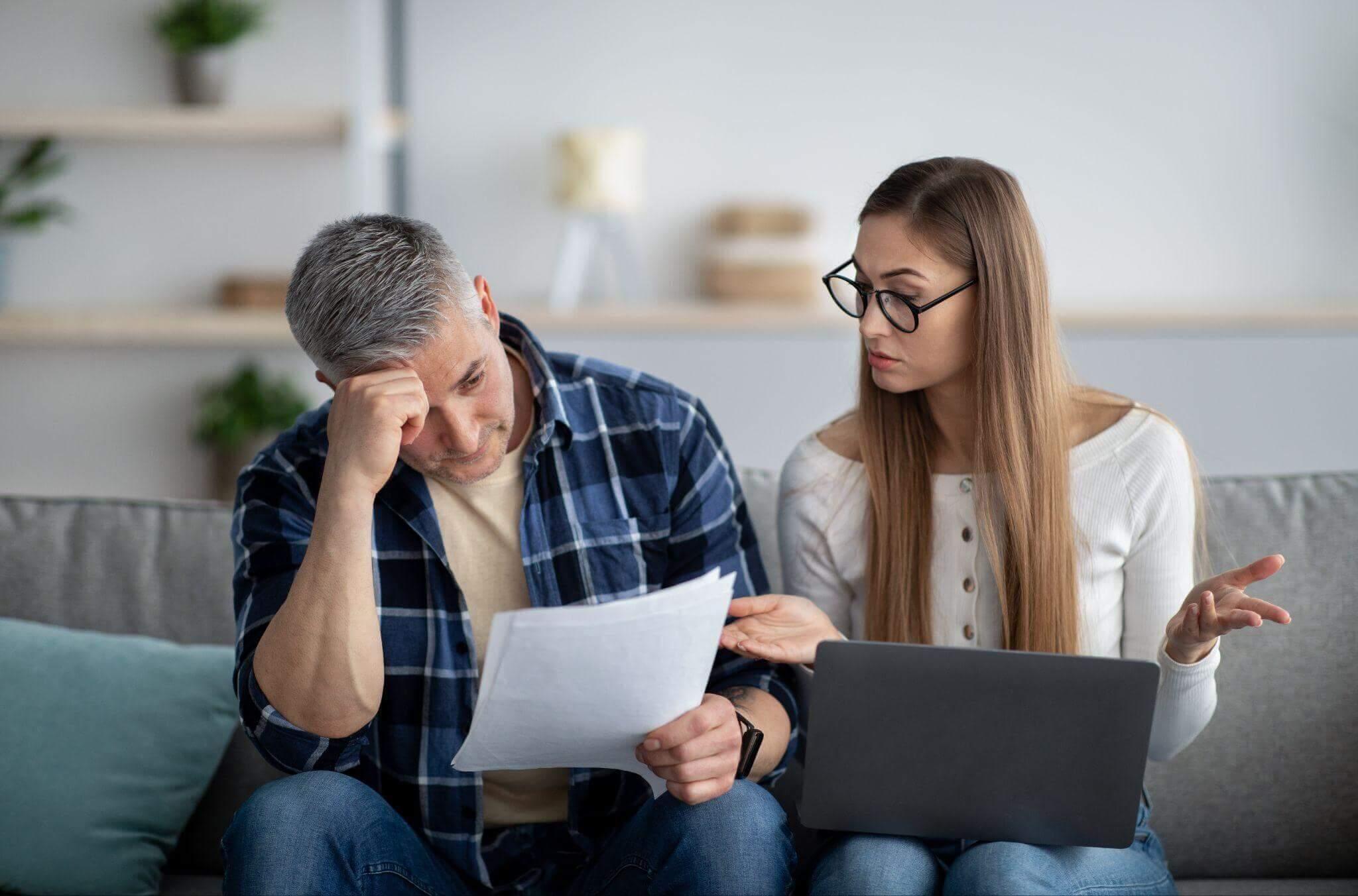 Couple reviewing financial documents on couch