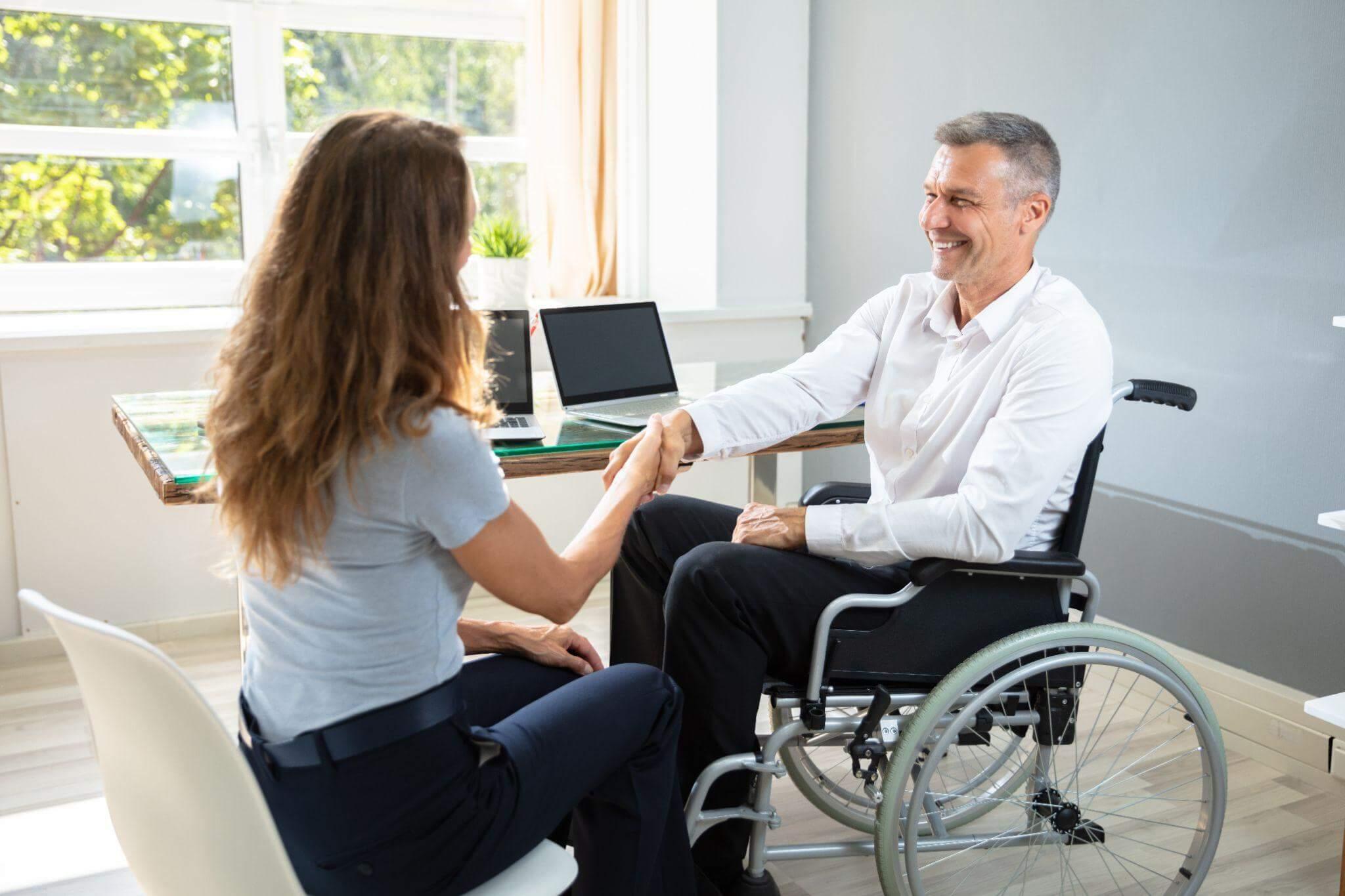 Man in wheelchair shaking hands with woman