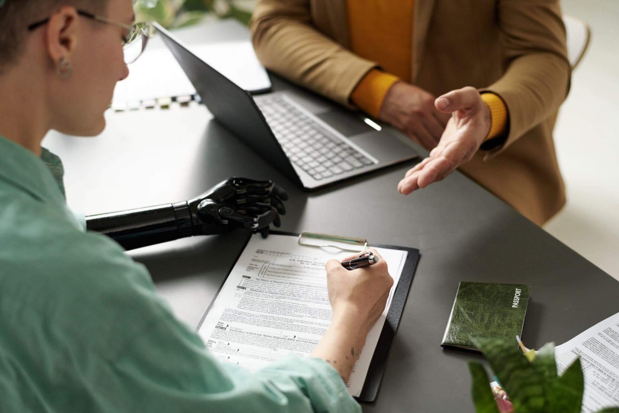 Two people discussing disability claims with laptops at a table