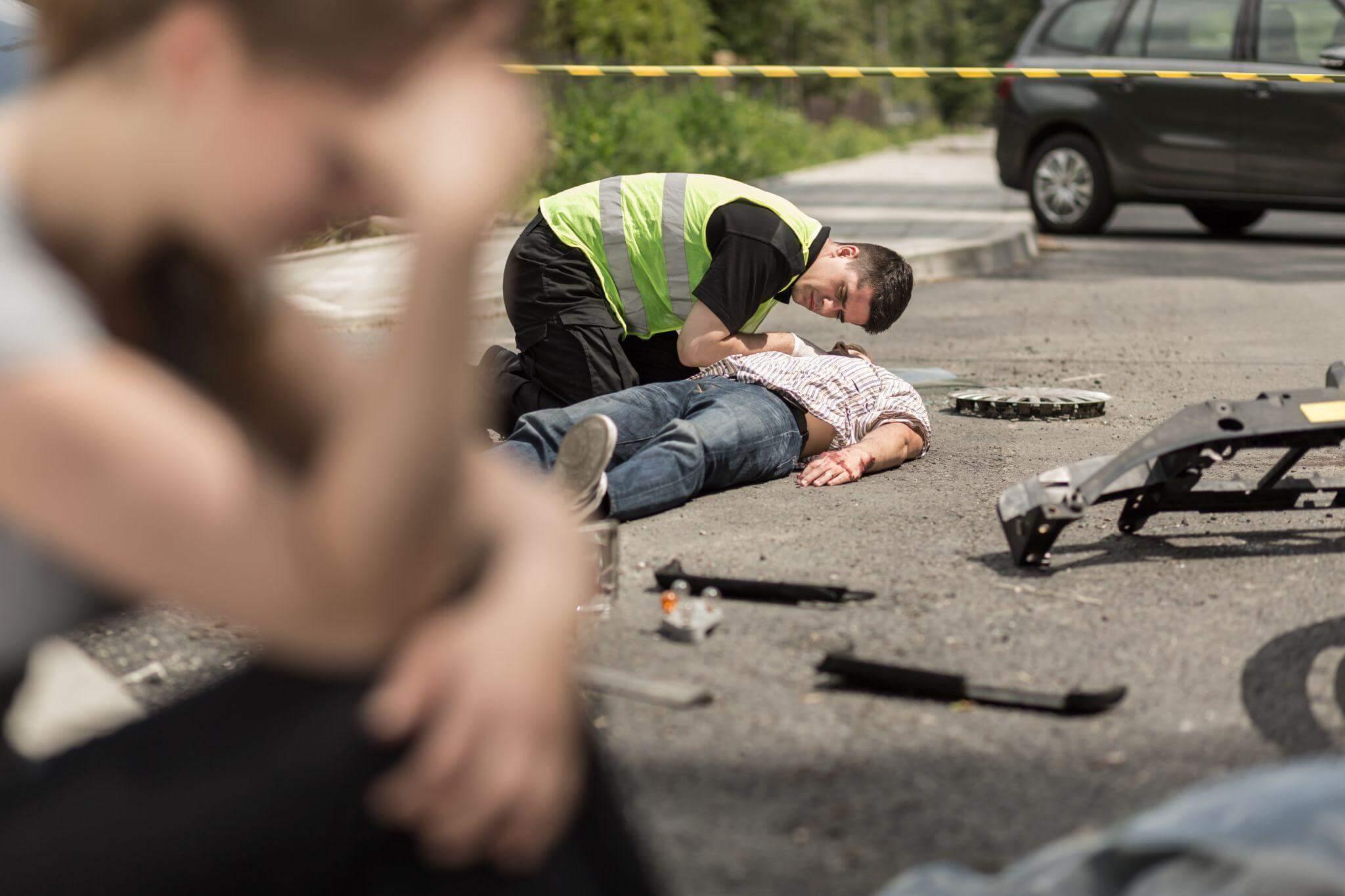 a man laying on the ground next to a car