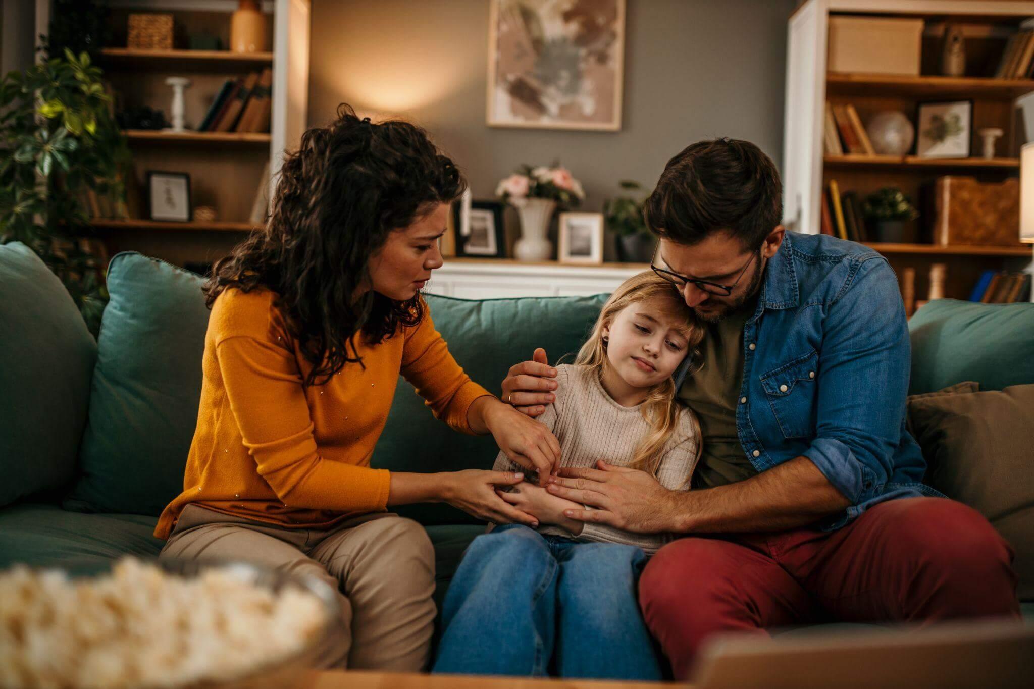 a man and a woman sitting on a couch with a little girl