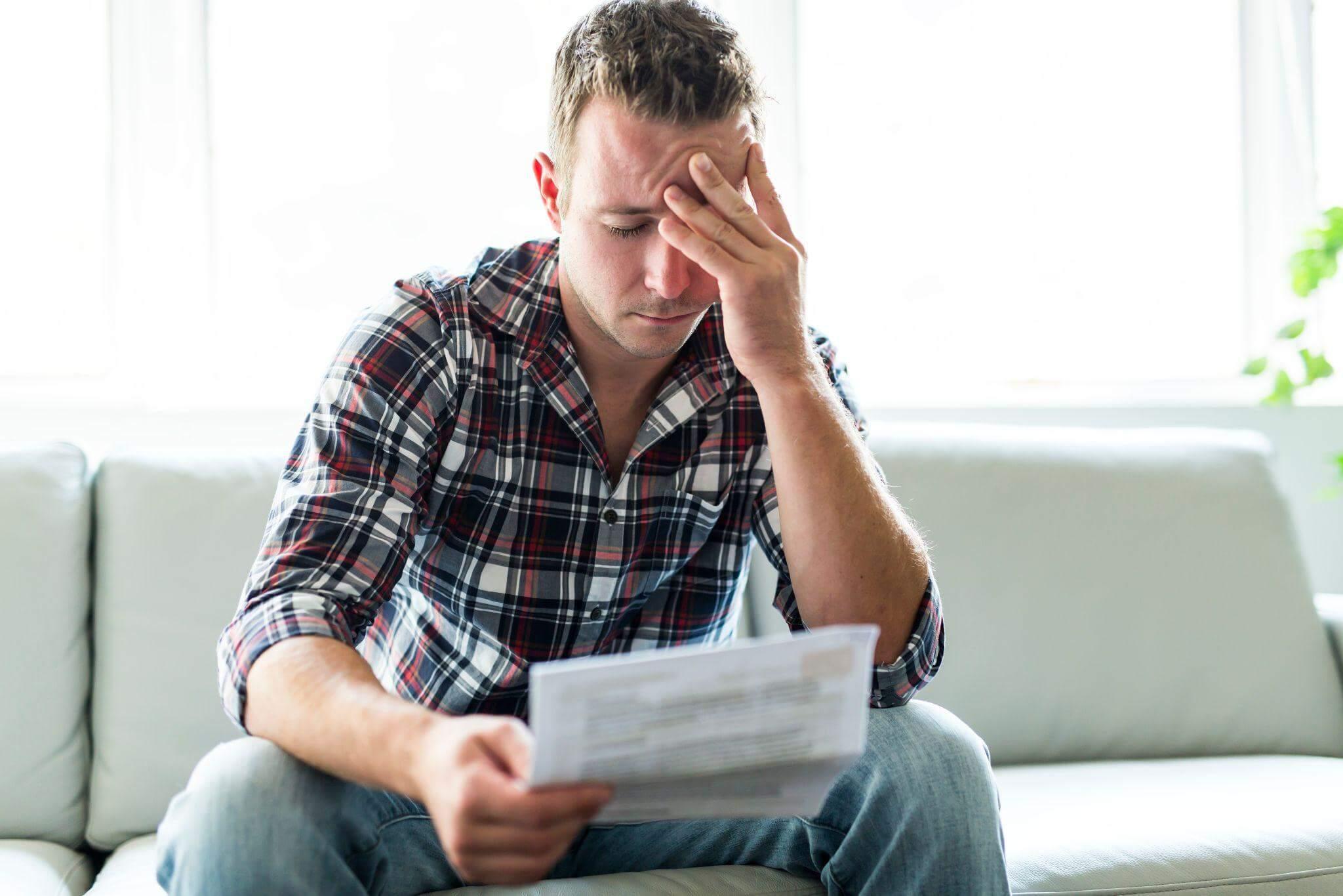 a man sitting on a couch holding a piece of paper