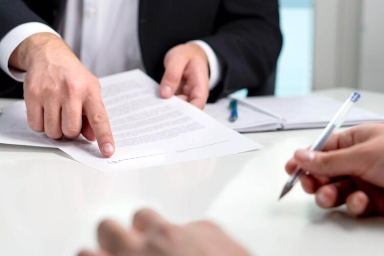 two-people-sitting-at-a-table-signing-papers.jpeg a man standing in front of a car talking on a cell phone