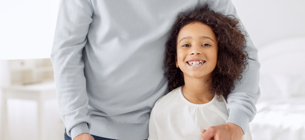father standing next to his smiling daughter
