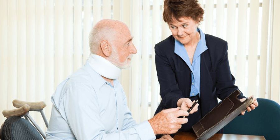 man in neck brace talking with lady at desk who is handing him a pen