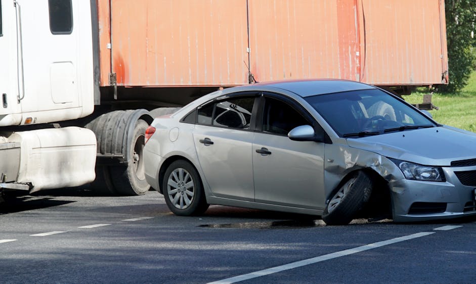 grey sudan hit on the front end by a semi-truck which is parked on the side of the road