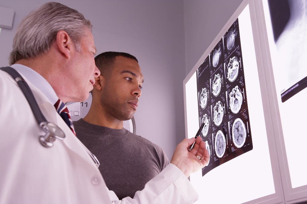 Doctor explains brain scan results to patient, highlighting images on a lightbox for medical consultation.