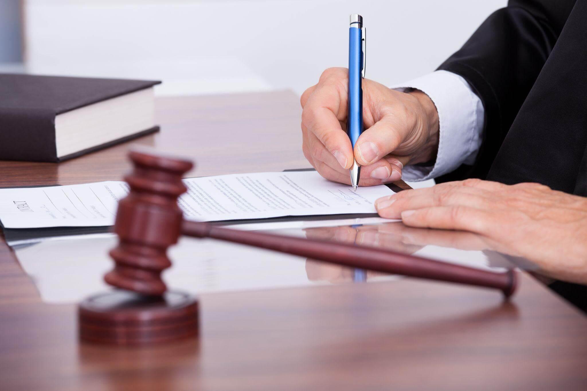 a man in a suit writing on a piece of paper next to a judge