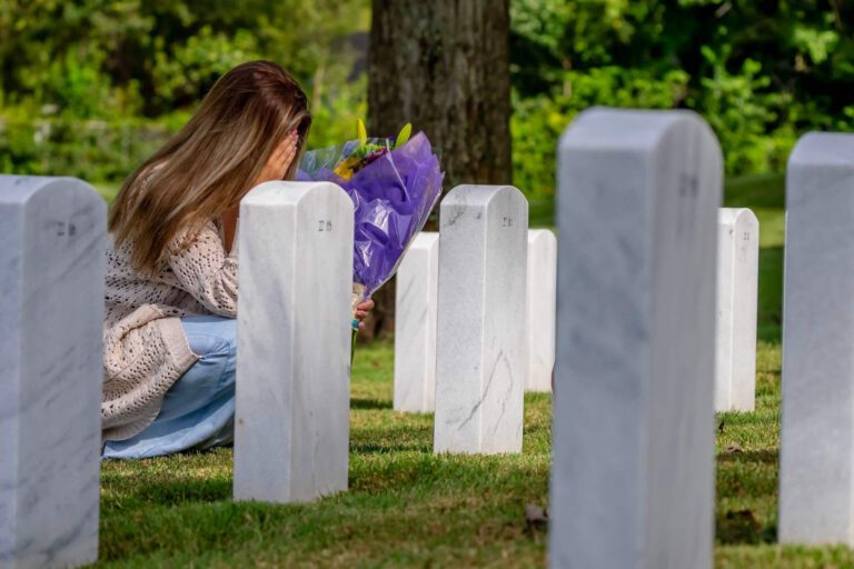 a woman kneeling down next to a bunch of headstones