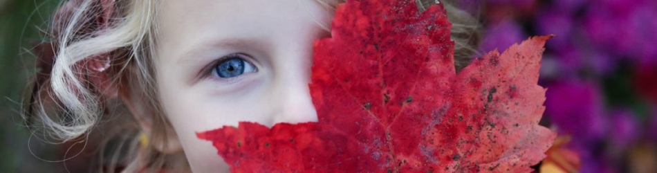 girl holding up a leaf over her face